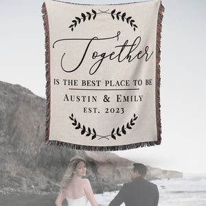 Together is the Best Place to Be Personalized Woven Throw Blanket. Customized with your first names and established year. Soft black text and laurel leaves adorn this design on natural white woven cotton background. Woven and made in the USA